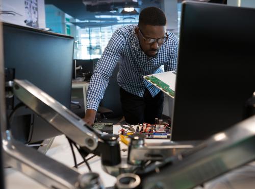 Man working over desk with electronics and computer