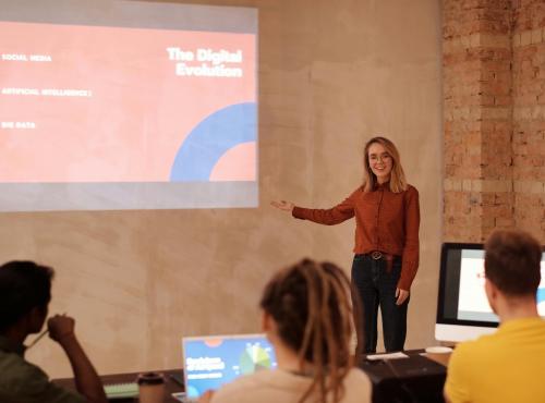 Person presenting to a class, pointing towards a powerpoint presentation which outlines the role of AI.