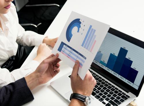 People considering charts on paper and laptop