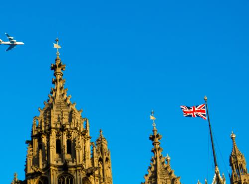 A light aircraft soars above the tips of the spires on the Palace of Westminster. The sky is a deep hue of blue on what is clearly a summer day.