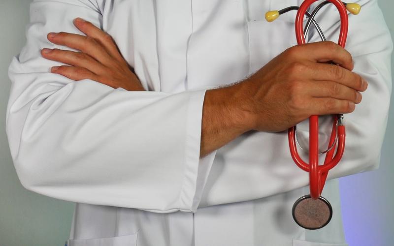 Person in a white medical coat holding a stethoscope. 