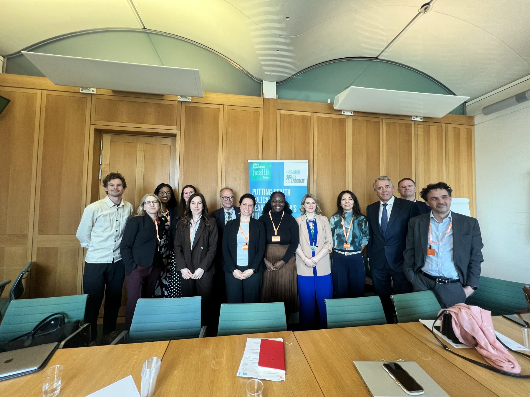 Steering group standing behind table, smiling at the camera.