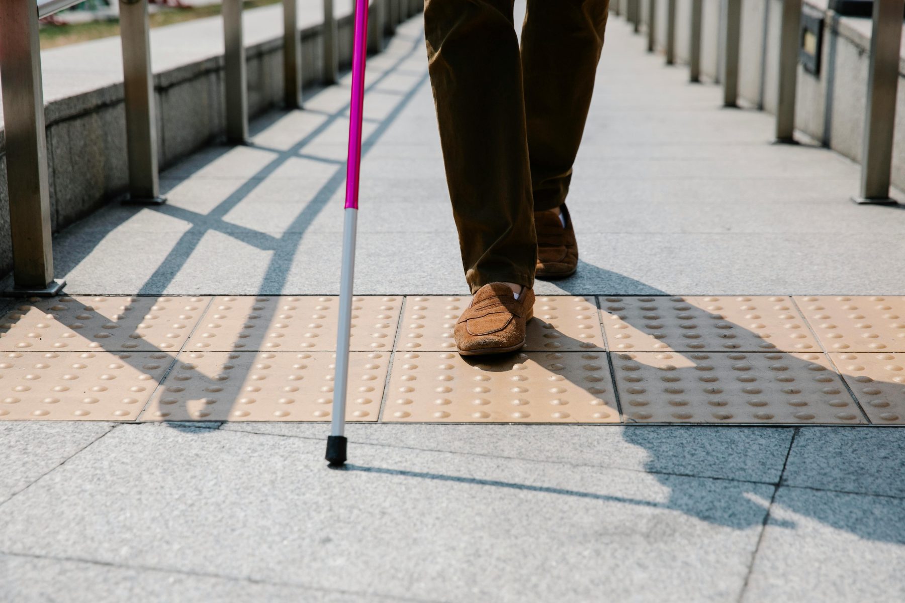 Person with mobility cane walking across pavement